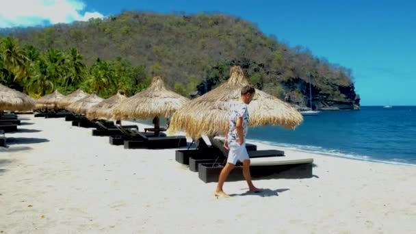 Fiatal férfiak fürdőruha, Sugar beach Saint Lucia, pálmafák és luxus strand székek a strandon a sziget St Lucia Karib-tenger — Stock videók