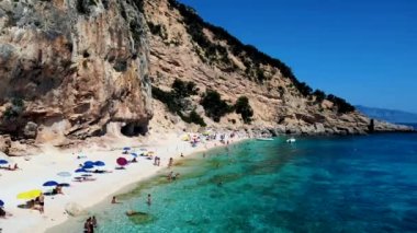 Golfo di Orosei Sardina, yukarıdan manzara, plaj şemsiyeleriyle dolu bir plaj manzarası ve turkuaz suda güneşlenen ve yüzen insanlar. Cala Gonone, Sardinya, İtalya, Cala Mariolu.