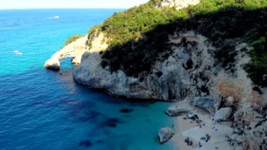 Golfo di Orosei Sardina, yukarıdan manzara, plaj şemsiyeleriyle dolu bir plaj manzarası ve turkuaz suda güneşlenen ve yüzen insanlar. Cala Gonone, Sardinya, İtalya, Cala Mariolu.