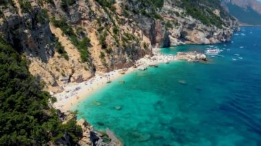 Golfo di Orosei Sardina, yukarıdan manzara, plaj şemsiyeleriyle dolu bir plaj manzarası ve turkuaz suda güneşlenen ve yüzen insanlar. Cala Gonone, Sardinya, İtalya, Cala Mariolu.