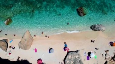 Golfo di Orosei Sardina, yukarıdan manzara, plaj şemsiyeleriyle dolu bir plaj manzarası ve turkuaz suda güneşlenen ve yüzen insanlar. Cala Gonone, Sardinya, İtalya, Cala Mariolu.