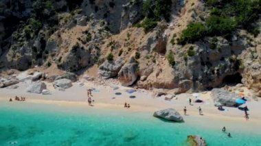 Golfo di Orosei Sardina, yukarıdan manzara, plaj şemsiyeleriyle dolu bir plaj manzarası ve turkuaz suda güneşlenen ve yüzen insanlar. Cala Gonone, Sardinya, İtalya, Cala Mariolu.