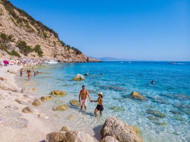 Golfo di Orosei Sardina, erkekler ve kadınlar plajda Sardunya İtalya 'da genç bir çift, Sardunya İtalya' da tatilde, birkaç erkek ve kadın, İtalya 'da kristal berrak mavi suyla okyanusta oynuyorlar.