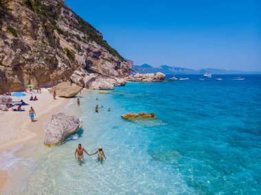 Golfo di Orosei Sardina, erkekler ve kadınlar plajda Sardunya İtalya 'da genç bir çift, Sardunya İtalya' da tatilde, birkaç erkek ve kadın, İtalya 'da kristal berrak mavi suyla okyanusta oynuyorlar.