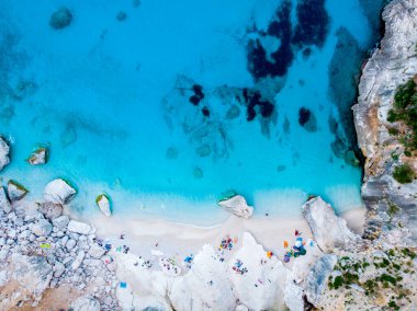 Golfo di Orosei Sardina, yukarıdan manzara, plaj şemsiyeleriyle dolu bir plaj manzarası ve turkuaz suda güneşlenen ve yüzen insanlar. Cala Gonone, Sardinya, İtalya, Cala Mariolu.