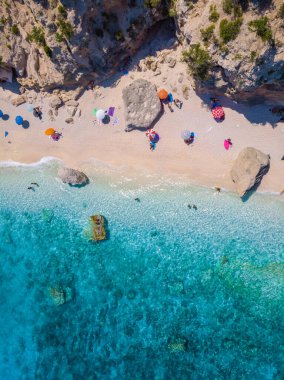 Golfo di Orosei Sardina, yukarıdan manzara, plaj şemsiyeleriyle dolu bir plaj manzarası ve turkuaz suda güneşlenen ve yüzen insanlar. Cala Gonone, Sardinya, İtalya, Cala Mariolu.