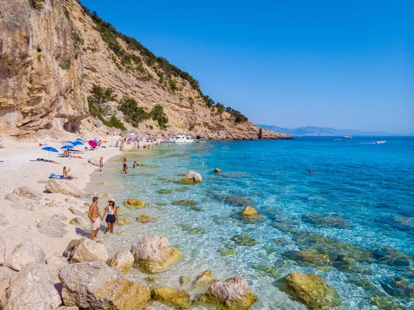 Golfo di Orosei Sardina, erkekler ve kadınlar plajda Sardunya İtalya 'da genç bir çift, Sardunya İtalya' da tatilde, birkaç erkek ve kadın, İtalya 'da kristal berrak mavi suyla okyanusta oynuyorlar.