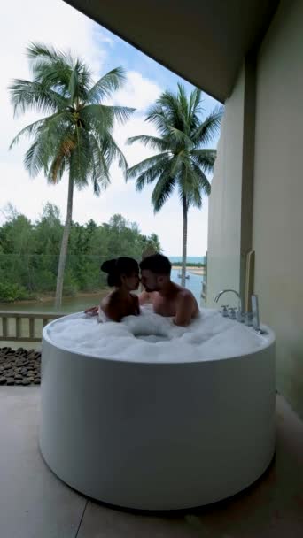 一对年轻貌美的情侣在泰国度豪华假期时在浴缸里放松的形象 欧洲男人和亚洲女人在浴缸里洗澡 — 图库视频影像
