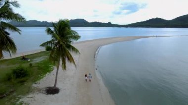 Ada Koh Yao Tayland 'da kumsalda yürüyen bir çift kadın ve erkek. Beyaz kum ve palmiye ağaçları olan bir kumsal..