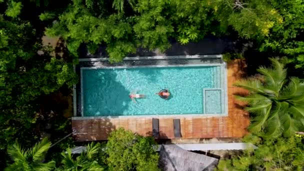 クラビ タイのジャングルの中のスイミングプールにいる男女2人タイのジャングルの中のスイミングプールの上にあるドローン付きの空中ビュー — ストック動画