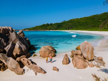 Anse Cocos plajı, La Digue Adası, Seyshelles, La Digue Seychelles 'in insansız hava görüntüsü. Tropik adanın kuş bakışı görüntüsü. Günbatımında plajda yürüyen birkaç erkek ve kadın.