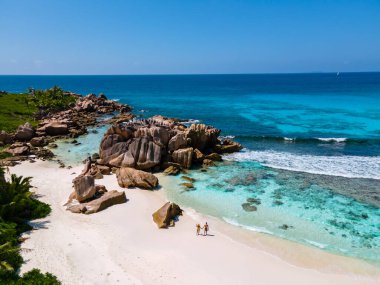 Anse Cocos plajı, La Digue Adası, Seyshelles, La Digue Seychelles 'in insansız hava görüntüsü. Tropik adanın kuş bakışı görüntüsü. Günbatımında plajda yürüyen birkaç erkek ve kadın.
