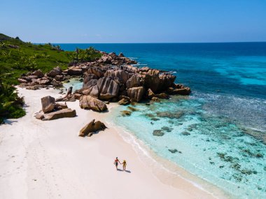 Anse Cocos plajı, La Digue Adası, Seyshelles, La Digue Seychelles 'in insansız hava görüntüsü. Tropik adanın kuş bakışı görüntüsü. Günbatımında plajda yürüyen birkaç erkek ve kadın.
