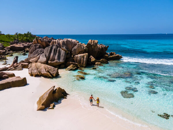 Anse Cocos beach, La Digue Island, Seyshelles, Drone aerial view of La Digue Seychelles bird eye view.of tropical Island, couple men and woman walking at the beach during sunset at a luxury vacation