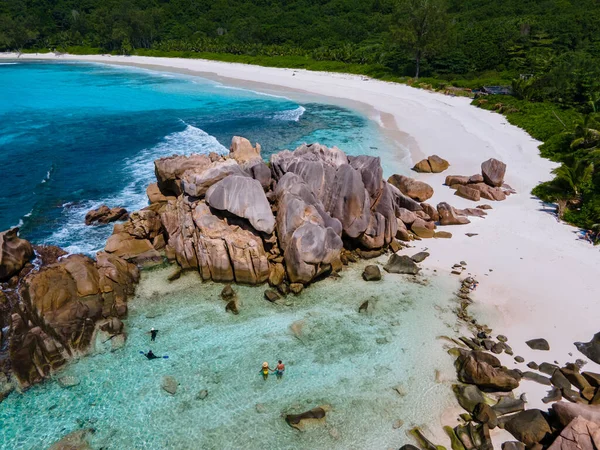 Anse Cocos plajı, La Digue Adası, Seyshelles, La Digue Seychelles 'in insansız hava görüntüsü. Tropik adanın kuş bakışı görüntüsü. Günbatımında plajda yürüyen birkaç erkek ve kadın.