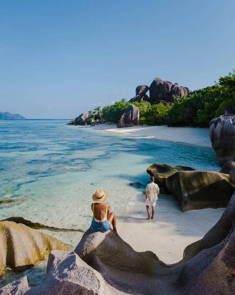 Anse Source dArgent plajı, La Digue Adası, Seyshelles, La Digue Seyşeller 'in insansız hava görüntüsü tropik adanın kuş bakışı görüntüsü, günbatımında sahilde yürüyen iki erkek ve kadın.