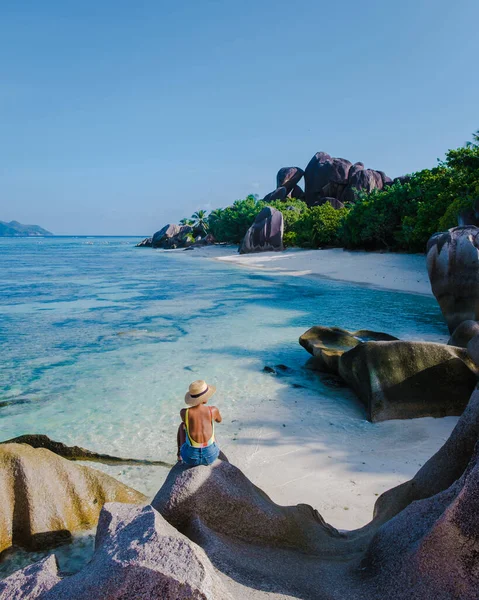 Anse Source dArgent plajı, La Digue Adası, Seyshelles, La Digue Seyşeller 'in insansız hava görüntüsü tropik adanın kuş bakışı görüntüsü, günbatımında sahilde yürüyen iki erkek ve kadın.