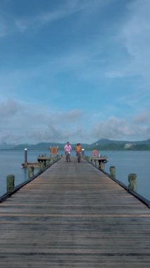 Tayland 'da Phuket yakınlarında bir tropikal adada bisiklete binen iki erkek ve bir kadın, Naka Adası' ndaki bir rıhtımda iki erkek ve bir kadın bisikleti.. 