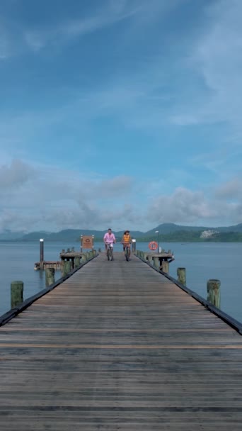 プーケットの近くの熱帯の島で自転車に乗っている男女のカップル ナカ島の桟橋で男と女の自転車 — ストック動画