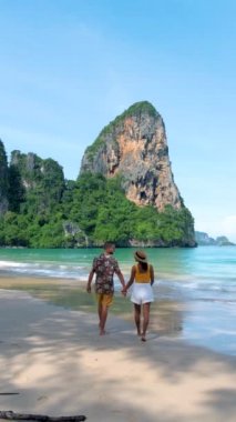 Railay Beach Krabi Tayland, bir çift Asyalı kadın ve Avrupalı erkek Railay Krabi 'nin tropik plajında yürüyorlar.. 