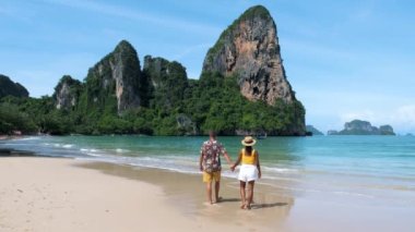 Railay Beach Krabi Tayland, bir çift Asyalı kadın ve Avrupalı erkek Railay Krabi 'nin tropik plajında yürüyorlar.. 