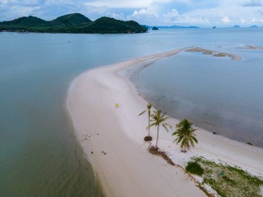 Ada Koh Yao Tayland 'da kumsalda yürüyen bir çift kadın ve erkek. Beyaz kum ve palmiye ağaçları olan bir kumsal..