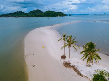 Ada Koh Yao Tayland 'da kumsalda yürüyen bir çift kadın ve erkek. Beyaz kum ve palmiye ağaçları olan bir kumsal..
