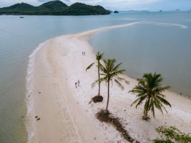 Ada Koh Yao Tayland 'da kumsalda yürüyen bir çift kadın ve erkek. Beyaz kum ve palmiye ağaçları olan bir kumsal..