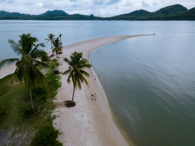 Ada Koh Yao Tayland 'da kumsalda yürüyen bir çift kadın ve erkek. Beyaz kum ve palmiye ağaçları olan bir kumsal..