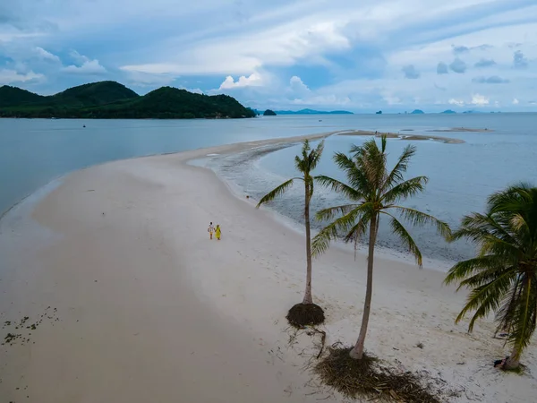 Ada Koh Yao Tayland 'da kumsalda yürüyen bir çift kadın ve erkek. Beyaz kum ve palmiye ağaçları olan bir kumsal..