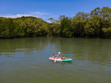 Tayland 'da Phuket Naka Adası' nda kayak yapan çift, tropik bir adada kayak yapan erkek ve kadın palmiye ağaçları ve mangrov ormanları olan. 