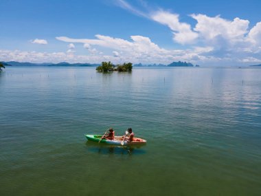 Tayland 'da Phuket Naka Adası' nda kayak yapan çift, tropik bir adada kayak yapan erkek ve kadın palmiye ağaçları ve mangrov ormanları olan. 