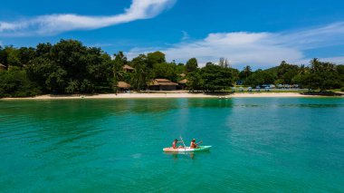 Tayland 'da Phuket Naka Adası' nda kayak yapan çift, tropik bir adada kayak yapan erkek ve kadın palmiye ağaçları ve mangrov ormanları olan. 