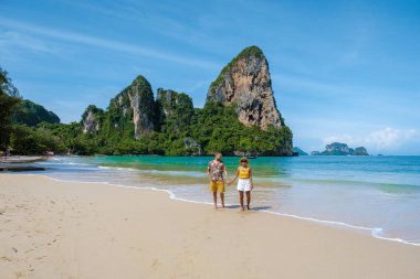 Railay Beach Krabi Tayland, Railay Krabi 'nin tropikal plajı, kumsalda bir çift kadın ve erkek, Tayland' da geleneksel uzun bir teknesi olan huzurlu Railay Kumsalı manzarası.. 
