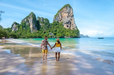 Railay Beach Krabi Tayland, Railay Krabi 'nin tropikal plajı, kumsalda bir çift kadın ve erkek, Tayland' da geleneksel uzun bir teknesi olan huzurlu Railay Kumsalı manzarası.. 