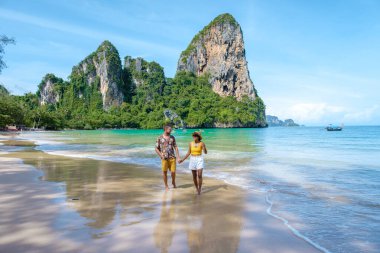Railay Beach Krabi Tayland, Railay Krabi 'nin tropikal plajı, kumsalda bir çift kadın ve erkek, Tayland' da geleneksel uzun bir teknesi olan huzurlu Railay Kumsalı manzarası.. 
