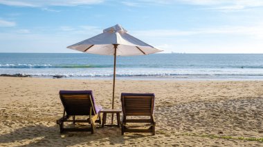 Koh Lanta plajında plaj sandalyeleri, Tayland 'da havuz kenarında şemsiyeli plaj sandalyeleri.