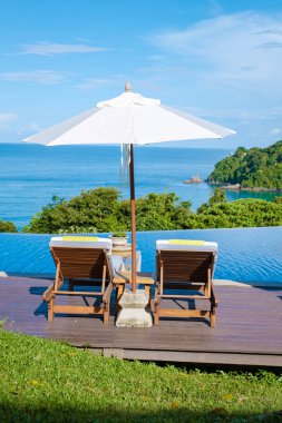 Koh Lanta plajında plaj sandalyeleri, Tayland 'da havuz kenarında şemsiyeli plaj sandalyeleri.