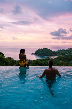Genç bir çift, tropik bir adada tatil yaparken yüzme havuzunda. Erkek ve kadın gün batımında sonsuz havuzda. Tayland 'da lüks bir havuz villasında lüks bir tatil.