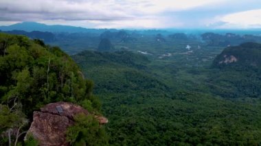 Ejderha Tepesi dağı Krabi Tayland, genç bir gezgin uçurumun üzerindeki kayanın üzerinde oturuyor, güzel bir manzarası var. Tayland, Krabi 'deki Khao Ngon Nak Doğa Yolu' nda Ejder Tepesi veya Khuan Sai.