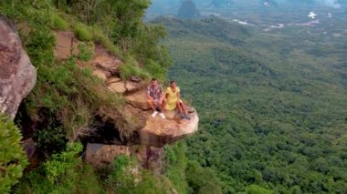 Ejderha Tepesi dağı Krabi Tayland, genç bir gezgin uçurumun üzerindeki kayanın üzerinde oturuyor, güzel bir manzarası var. Tayland, Krabi 'deki Khao Ngon Nak Doğa Yolu' nda Ejder Tepesi veya Khuan Sai.