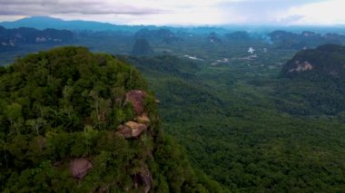 Ejderha Tepesi dağı Krabi Tayland, genç bir gezgin uçurumun üzerindeki kayanın üzerinde oturuyor, güzel bir manzarası var. Tayland, Krabi 'deki Khao Ngon Nak Doğa Yolu' nda Ejder Tepesi veya Khuan Sai.