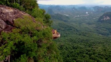 Ejderha Tepesi dağı Krabi Tayland, genç bir gezgin uçurumun üzerindeki kayanın üzerinde oturuyor, güzel bir manzarası var. Tayland, Krabi 'deki Khao Ngon Nak Doğa Yolu' nda Ejder Tepesi veya Khuan Sai.