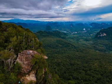 Ejderha Tepesi dağı Krabi Tayland, genç bir gezgin uçurumun üzerindeki kayanın üzerinde oturuyor, güzel bir manzarası var. Tayland, Krabi 'deki Khao Ngon Nak Doğa Yolu' nda Ejder Tepesi veya Khuan Sai.
