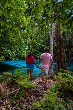 Zümrüt havuz ve mavi havuz, ağaçlar ve kristal berrak suyla kaplı mangrovlar Krabi Eyaleti, Tayland 'da. Bir çift erkek ve bir kadın mavi havuzu ziyaret ediyor.