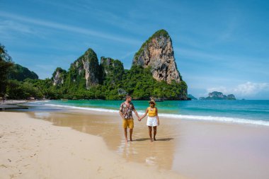 Railay Beach Krabi Tayland, Railay Krabi 'nin tropikal plajı, kumsalda bir çift kadın ve erkek, Tayland' da geleneksel uzun bir teknesi olan huzurlu Railay Kumsalı manzarası.. 