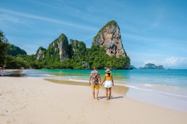 Railay Beach Krabi Tayland, Railay Krabi 'nin tropikal plajı, kumsalda bir çift kadın ve erkek, Tayland' da geleneksel uzun bir teknesi olan huzurlu Railay Kumsalı manzarası.. 