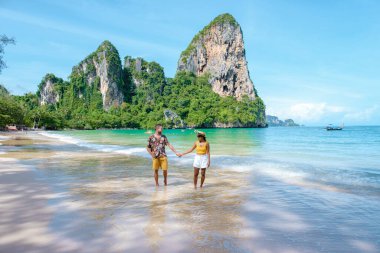 Railay Beach Krabi Tayland, Railay Krabi 'nin tropikal plajı, kumsalda bir çift kadın ve erkek, Tayland' da geleneksel uzun bir teknesi olan huzurlu Railay Kumsalı manzarası.. 