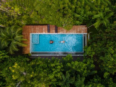 Krabi Tayland 'ın ormanında yüzme havuzunun hava aracı görüntüsü, Tayland ormanında yüzme havuzunun üstünde insansız hava aracı. Havuzdaki çift erkek ve kadın yukarıdan