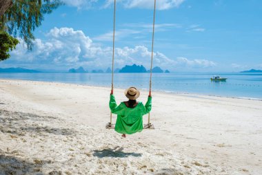 Phuket Tayland yakınlarındaki tropikal ada Naka Adası sahilinde bir kadın, Tayland 'da salıncakta sallanan bir kadın.